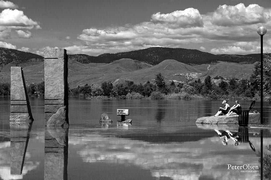 Kamloops black and white photo of people sitting on a rock in the middle of a lake