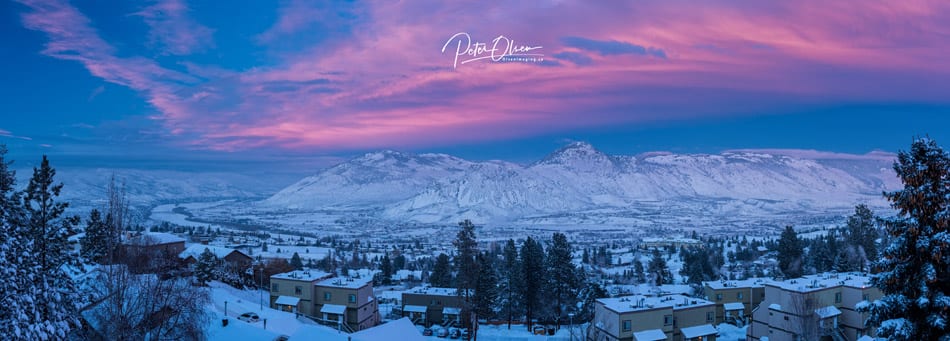 Kamloops City pink and blue sky with snow-covered mountains and ground with trees and buildings