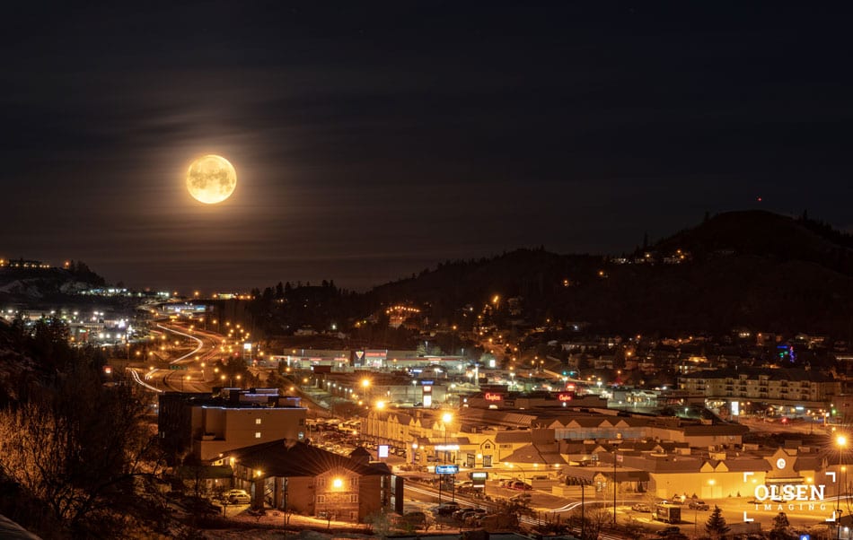 full moon in the night sky with city lights brightly lit