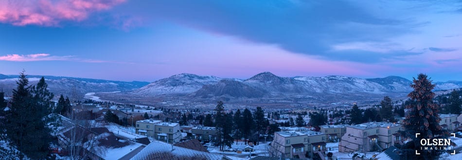 panoramic view of a blue and pink sky with mountains and a city