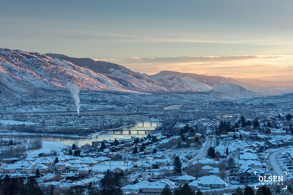 white snow-covered city with mountains and pink and blue sky