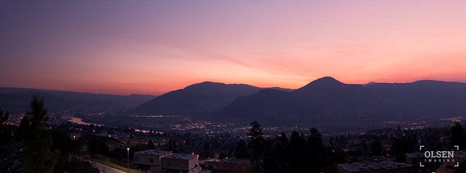 pink blue and white sky with mountains and trees with city