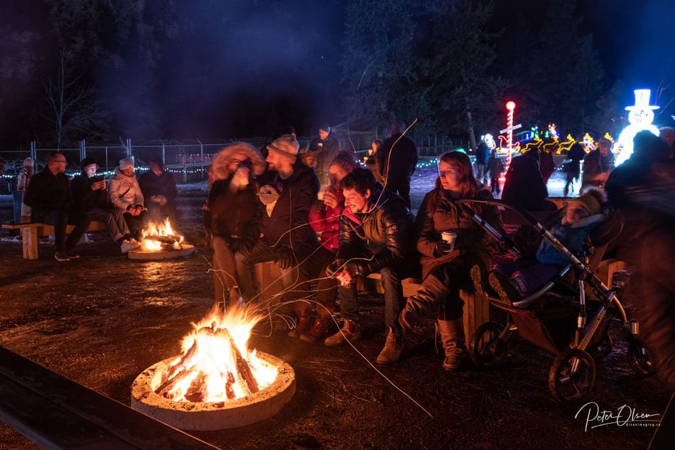 people seated on wooden benches looking at a campfire celebrating