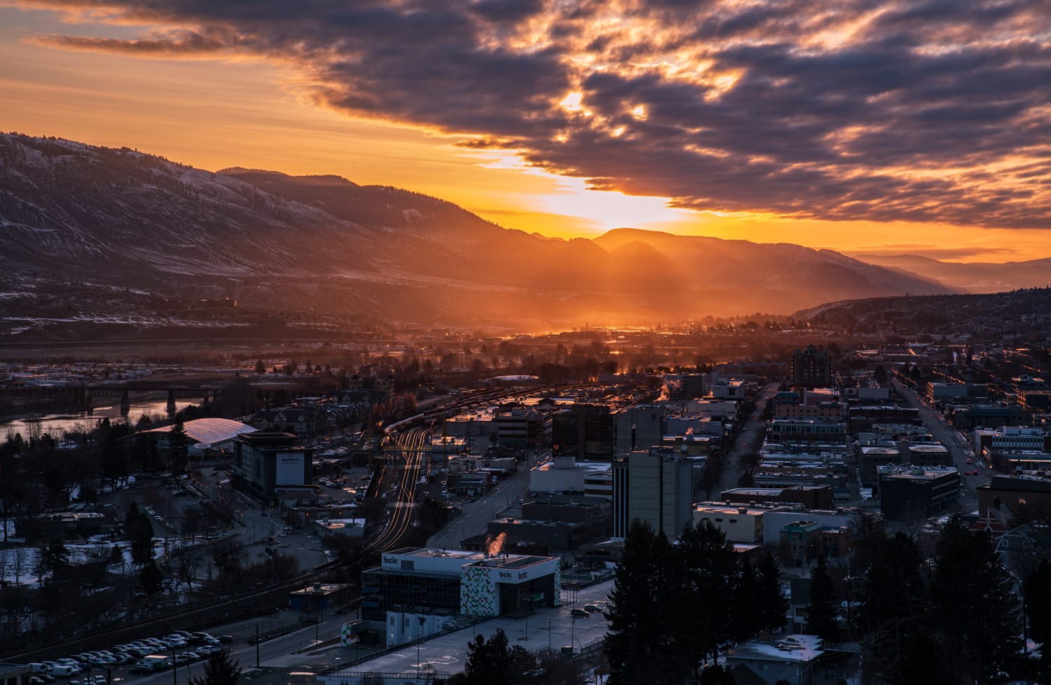 Kamloops City closeup of city with clouds and setting sun with mountains