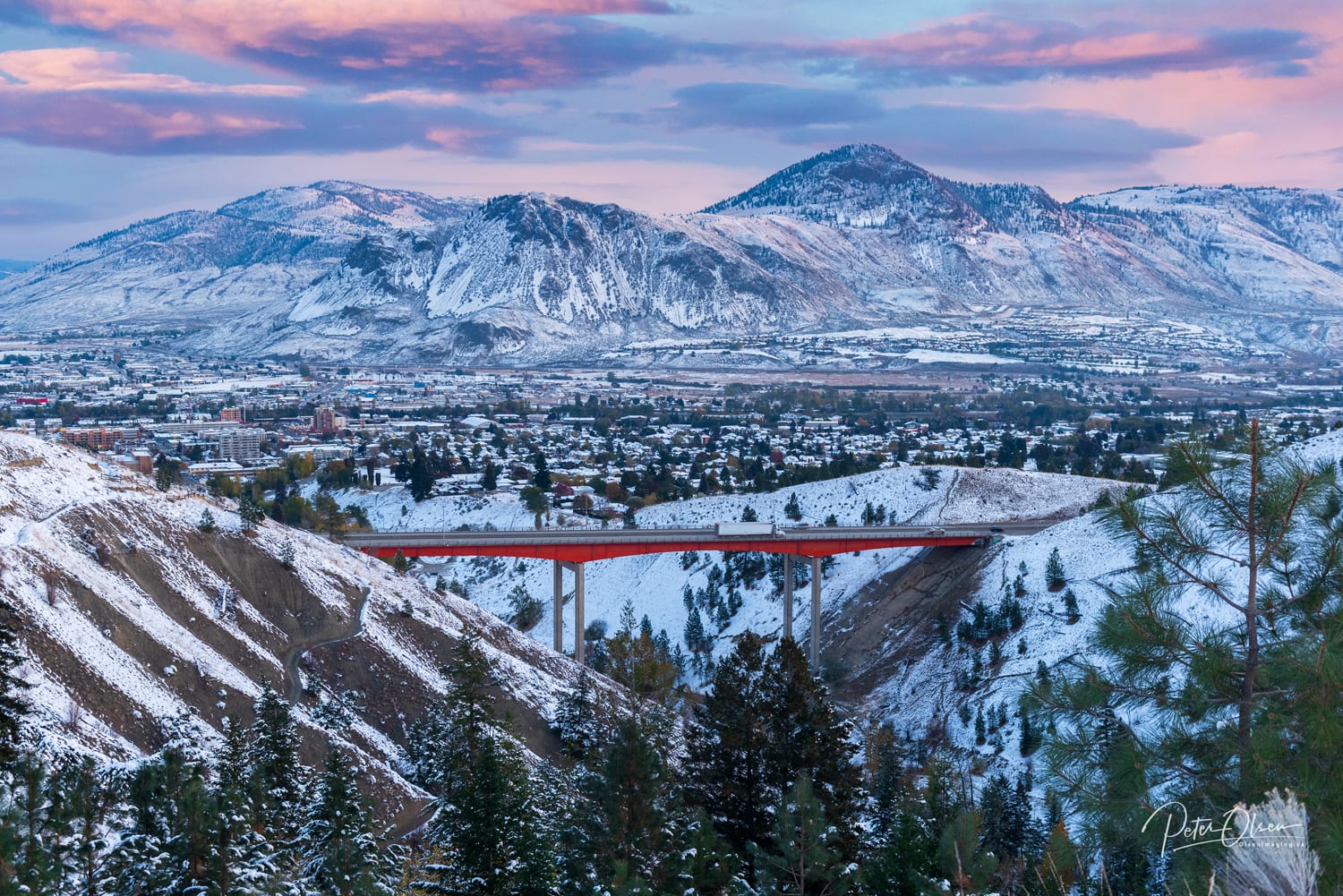 snowy mountain view with bright red train tracks to the city with pink and purple sky