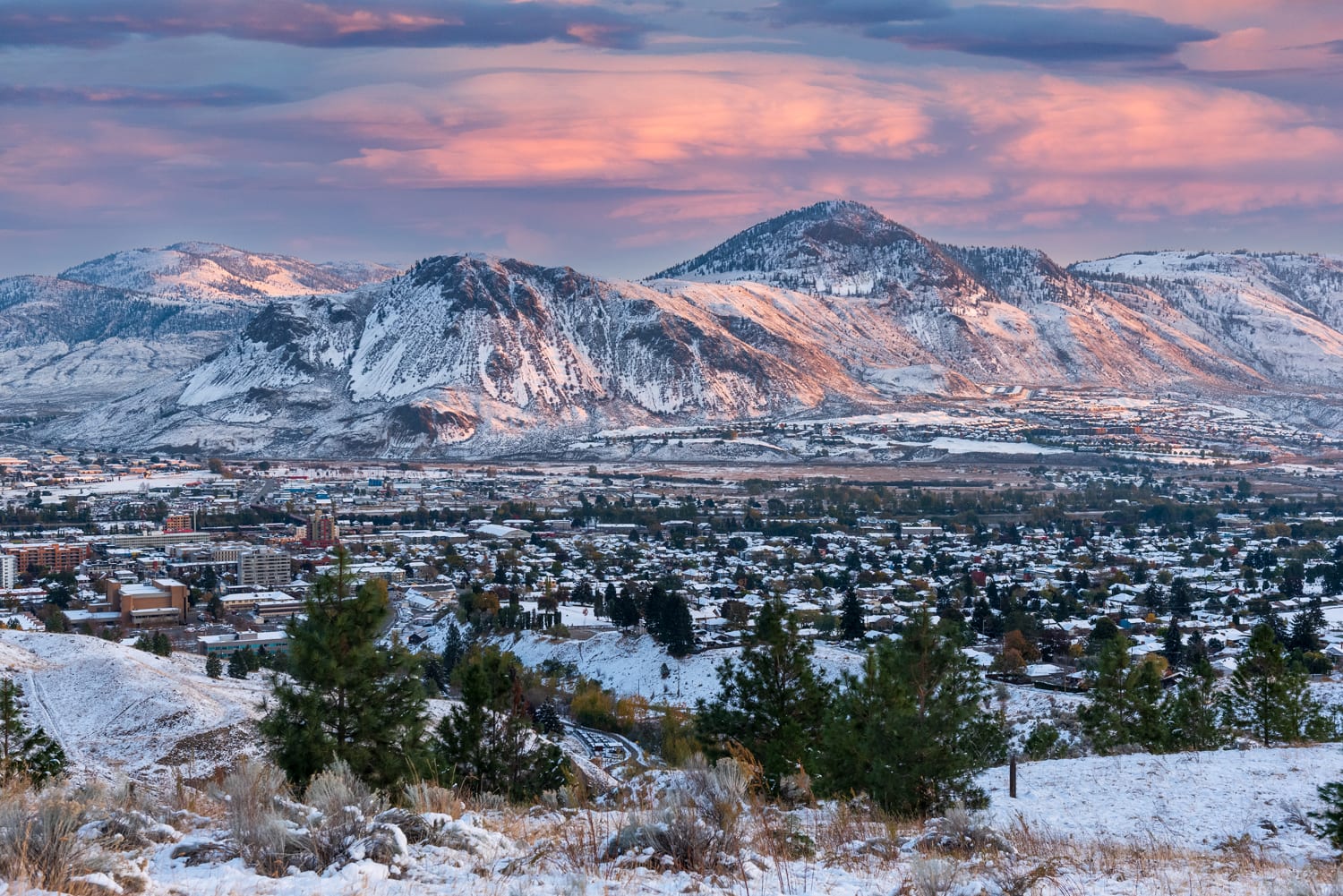 snowy mountains and city with pink and blue clouds and sky