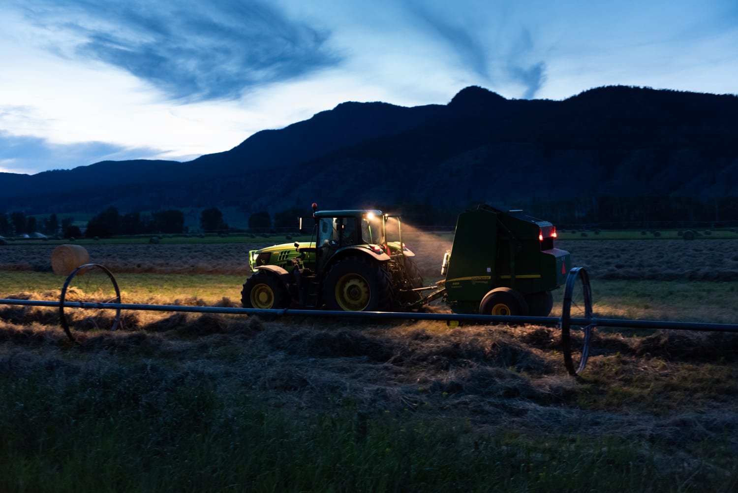 Kamloops rural life tractor with lights in field with blue sky and clouds