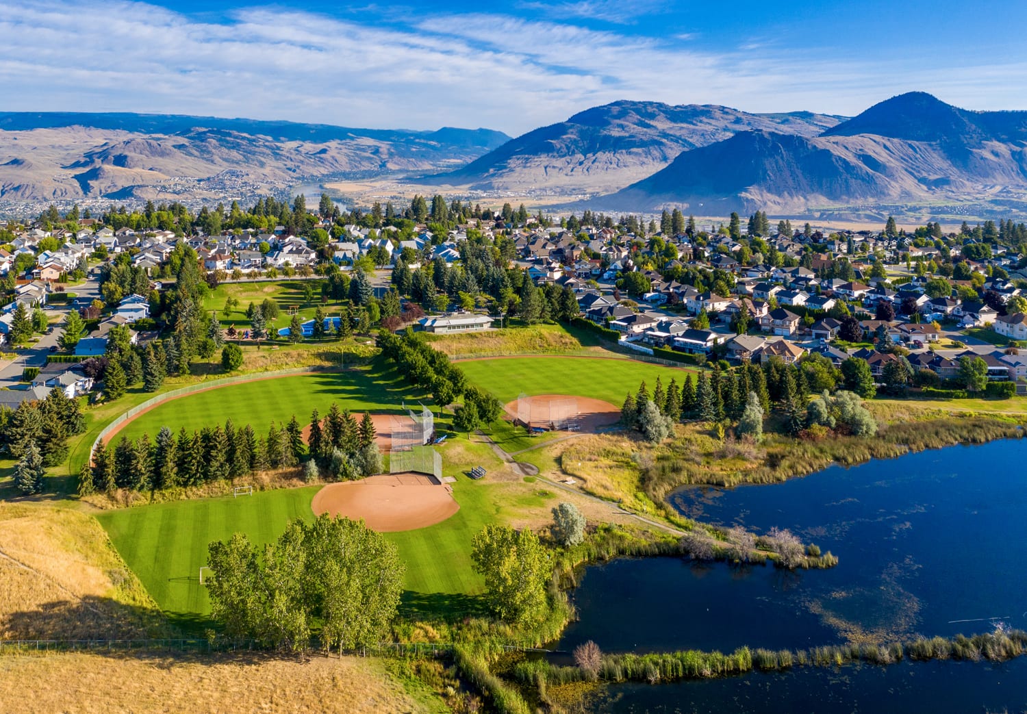 Kamloops City Aerial trees and lawn with river and mountains with sky