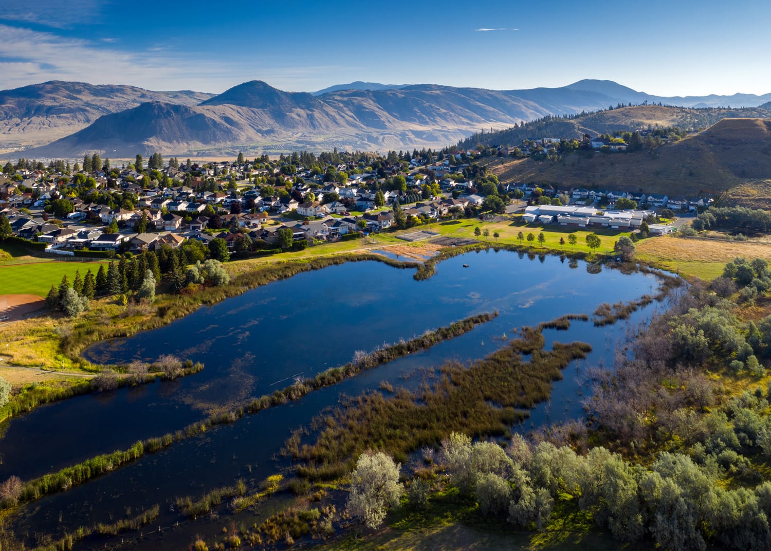 Kamloops City Aerial lake with trees and buildings with mountains