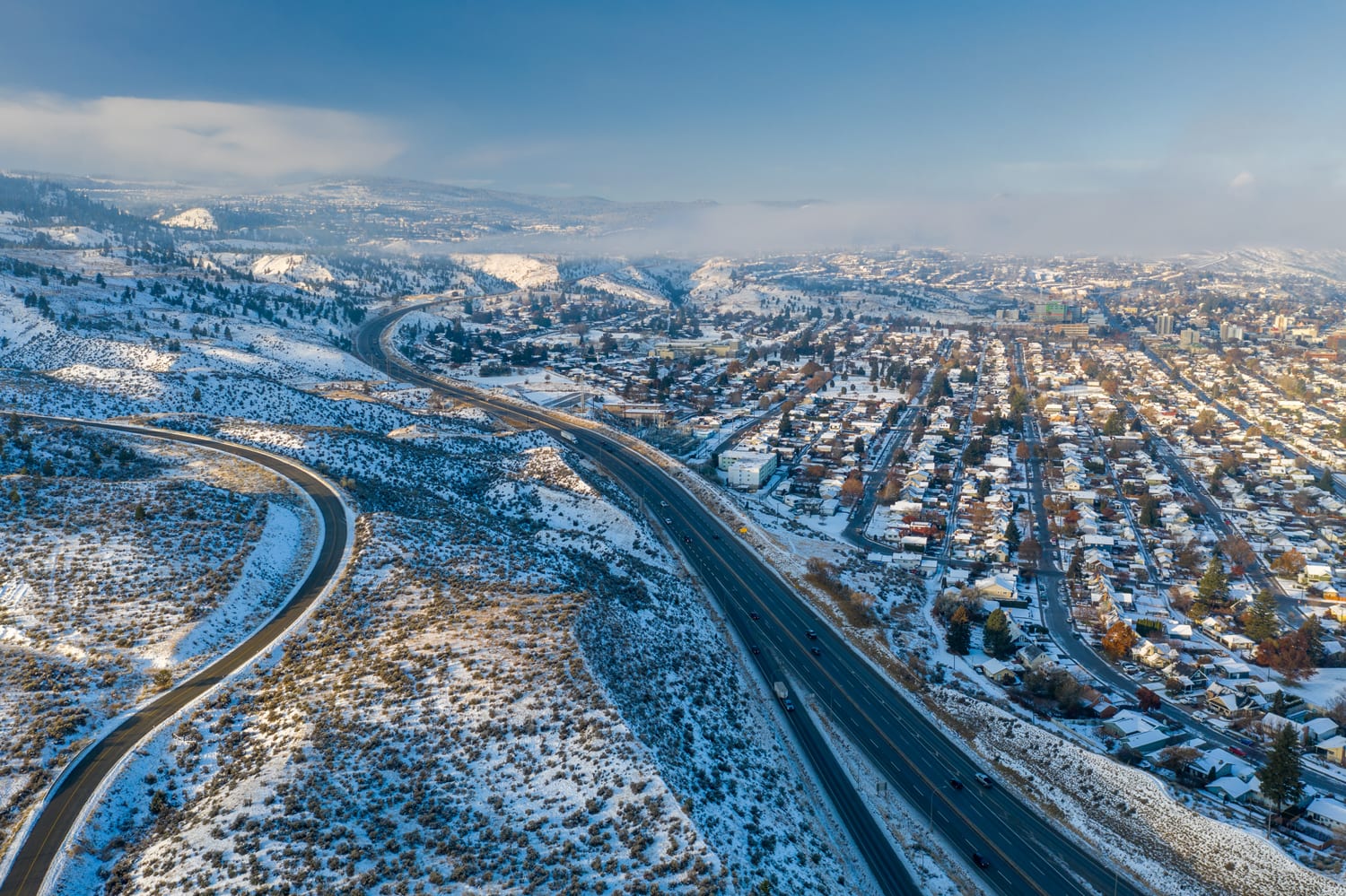 Kamloops City Aerial winding road with trees and snow with city