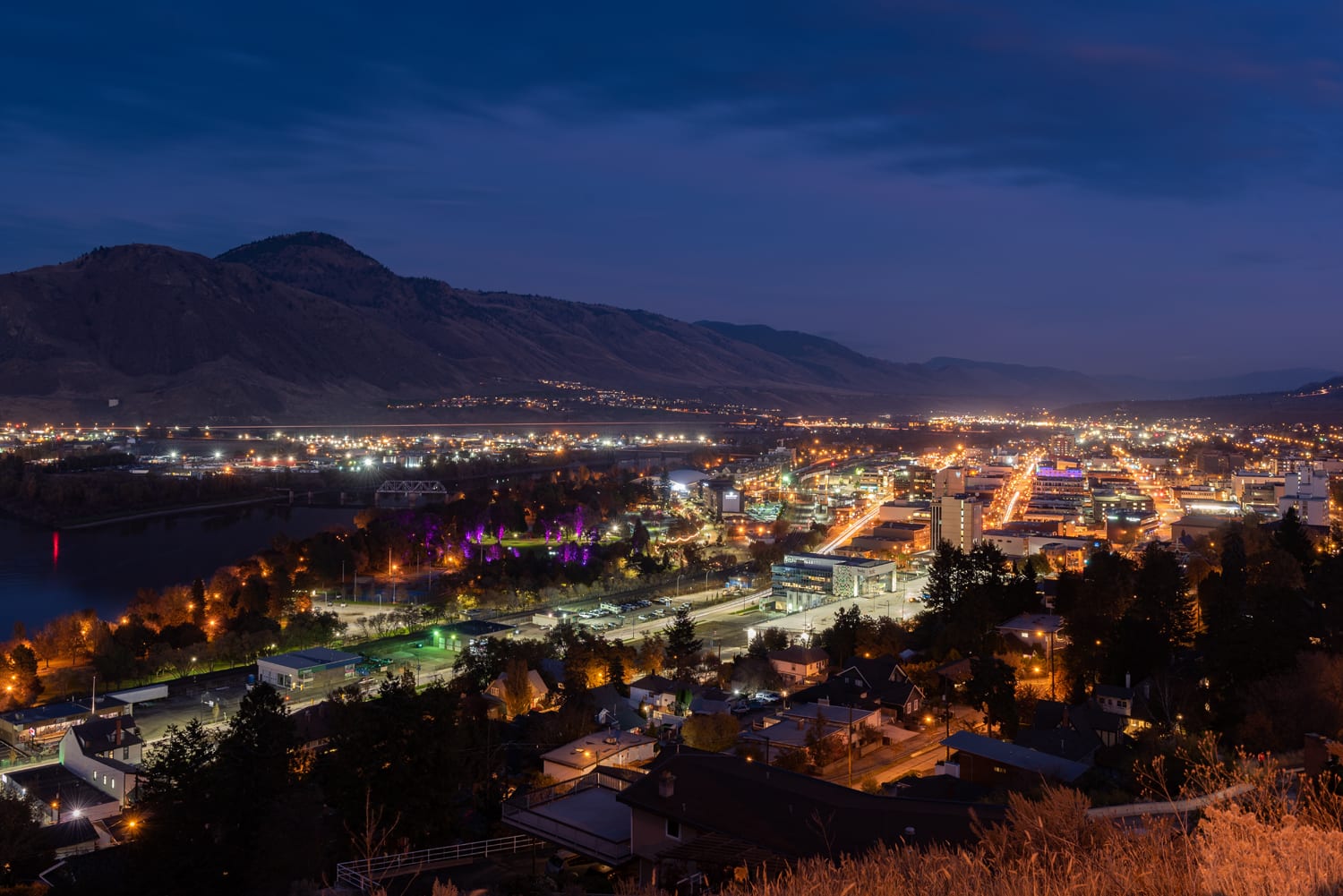 HDR view of city at night with the lake and tall blue mountains