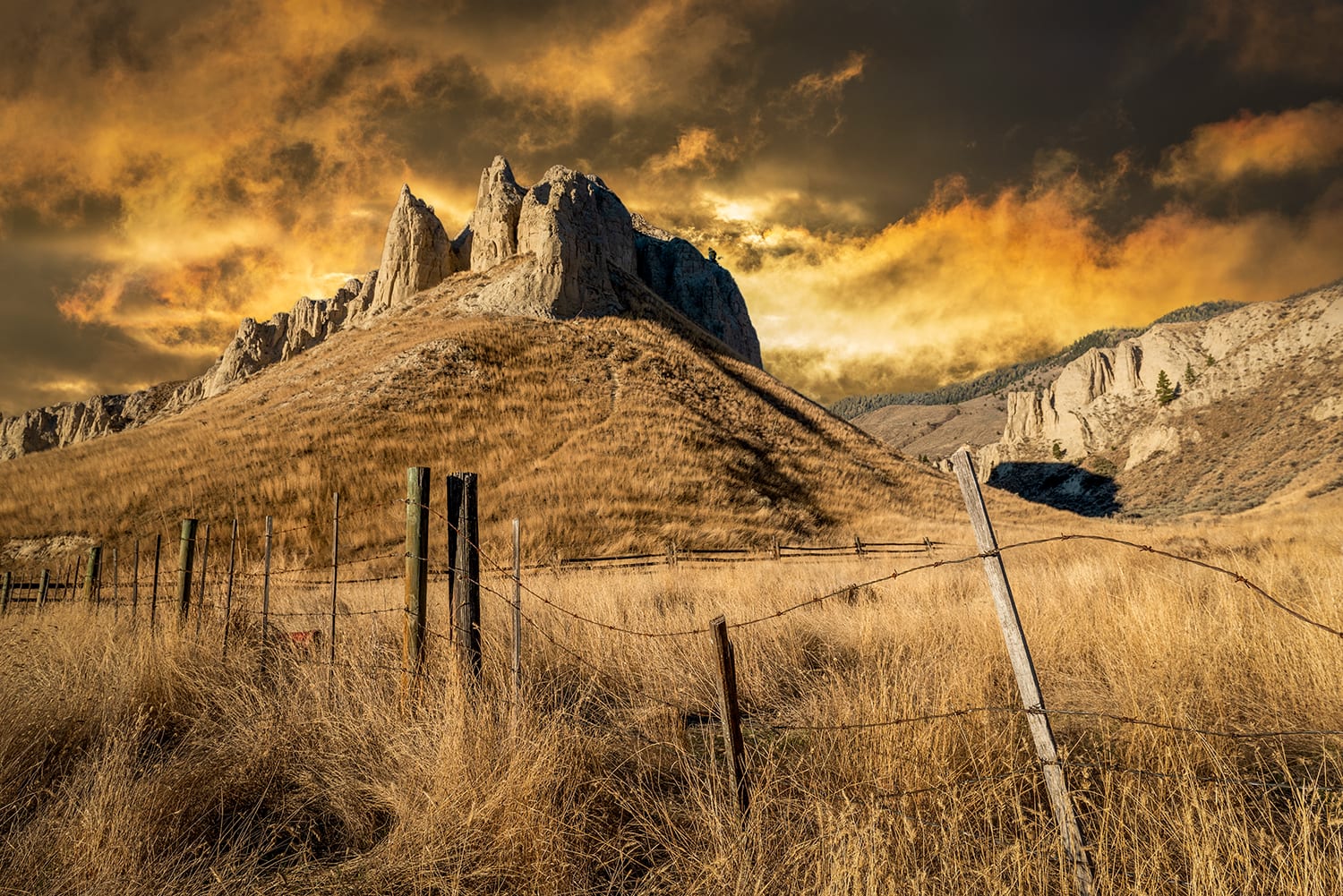 Kamloops Landscape with yellow and grey sky with wooden fence with rocky mountain