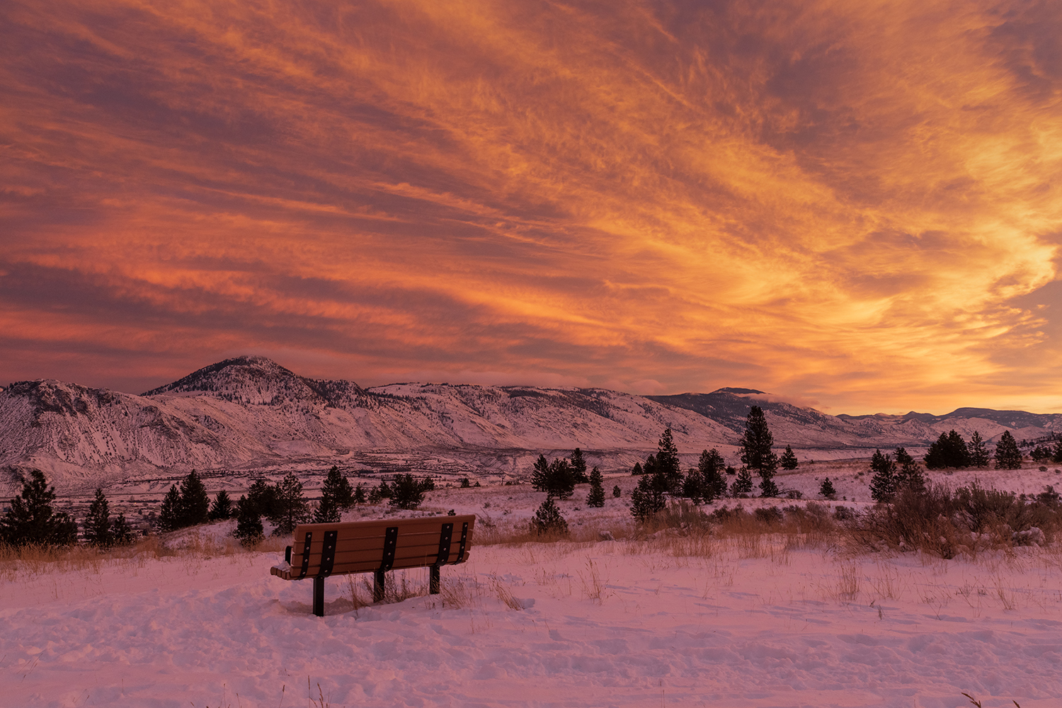 Kamloops Landscape snow with wooden bench and orange and red sky
