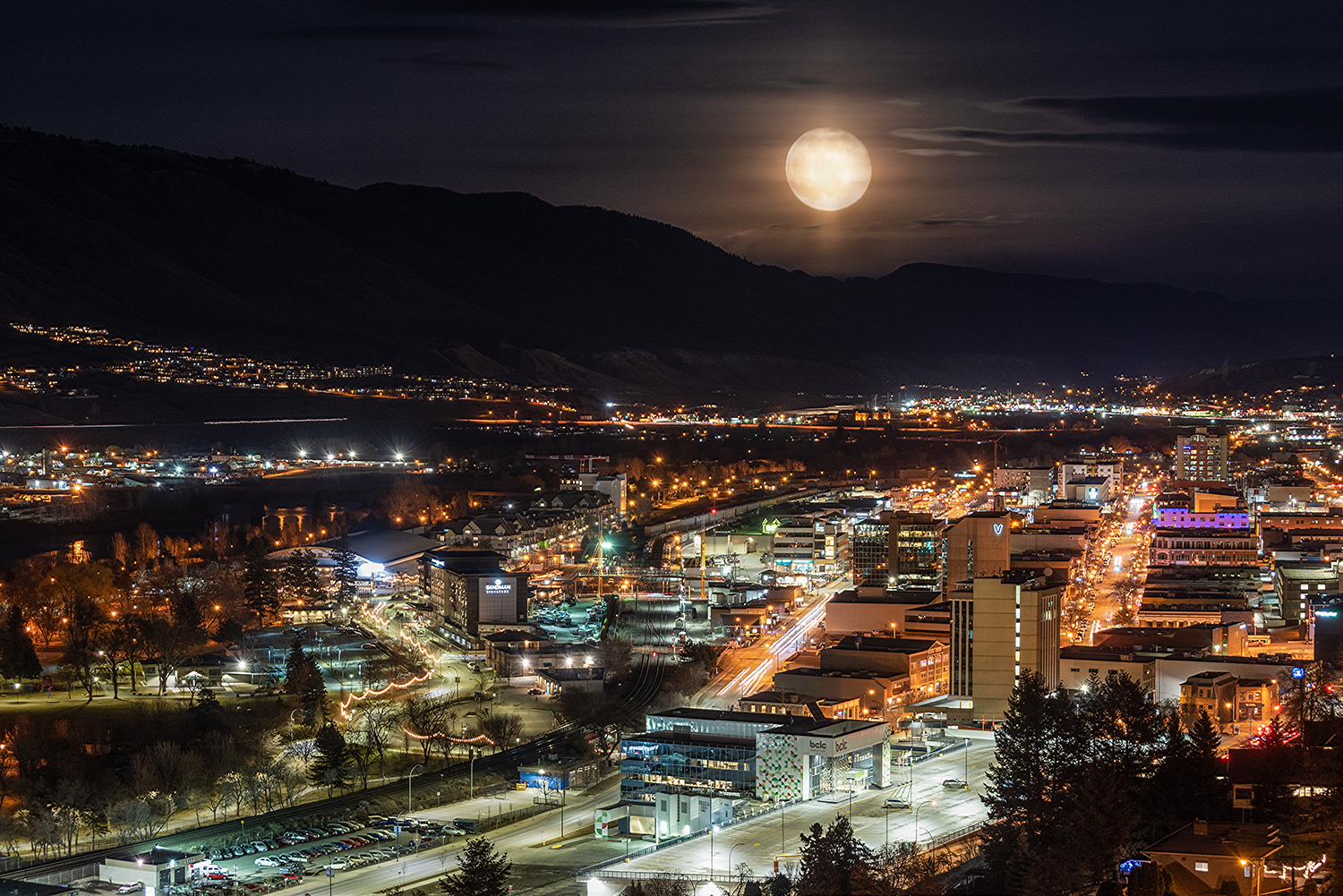 nightlife of city with hazy full moon and mountain