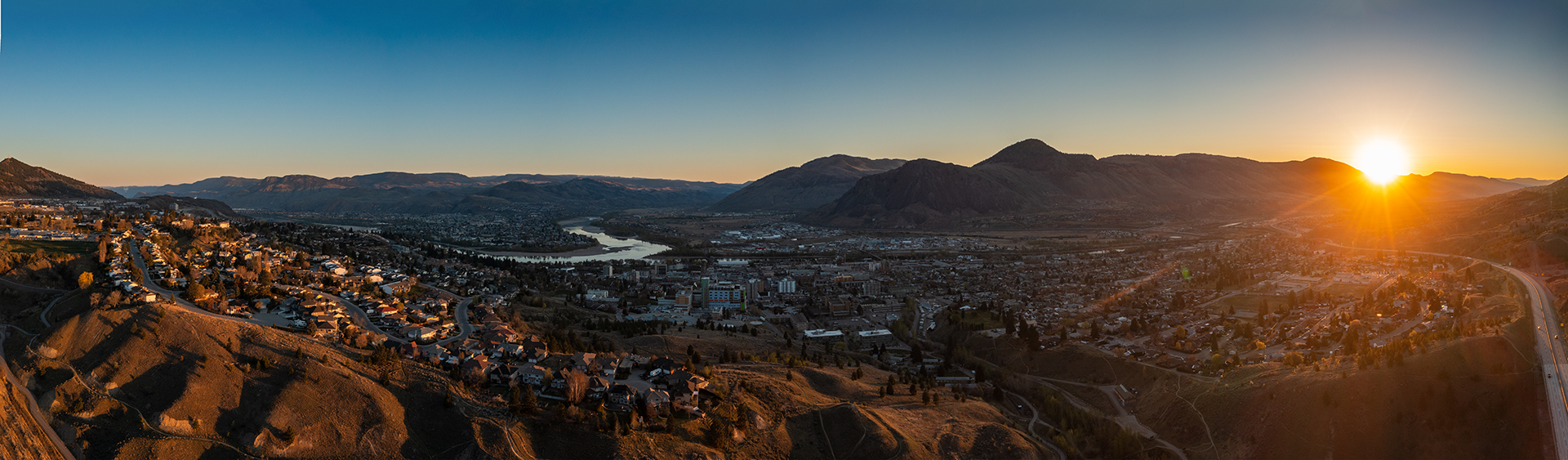 Kamloops City Aerial bright sun rising over mountains and blue sky