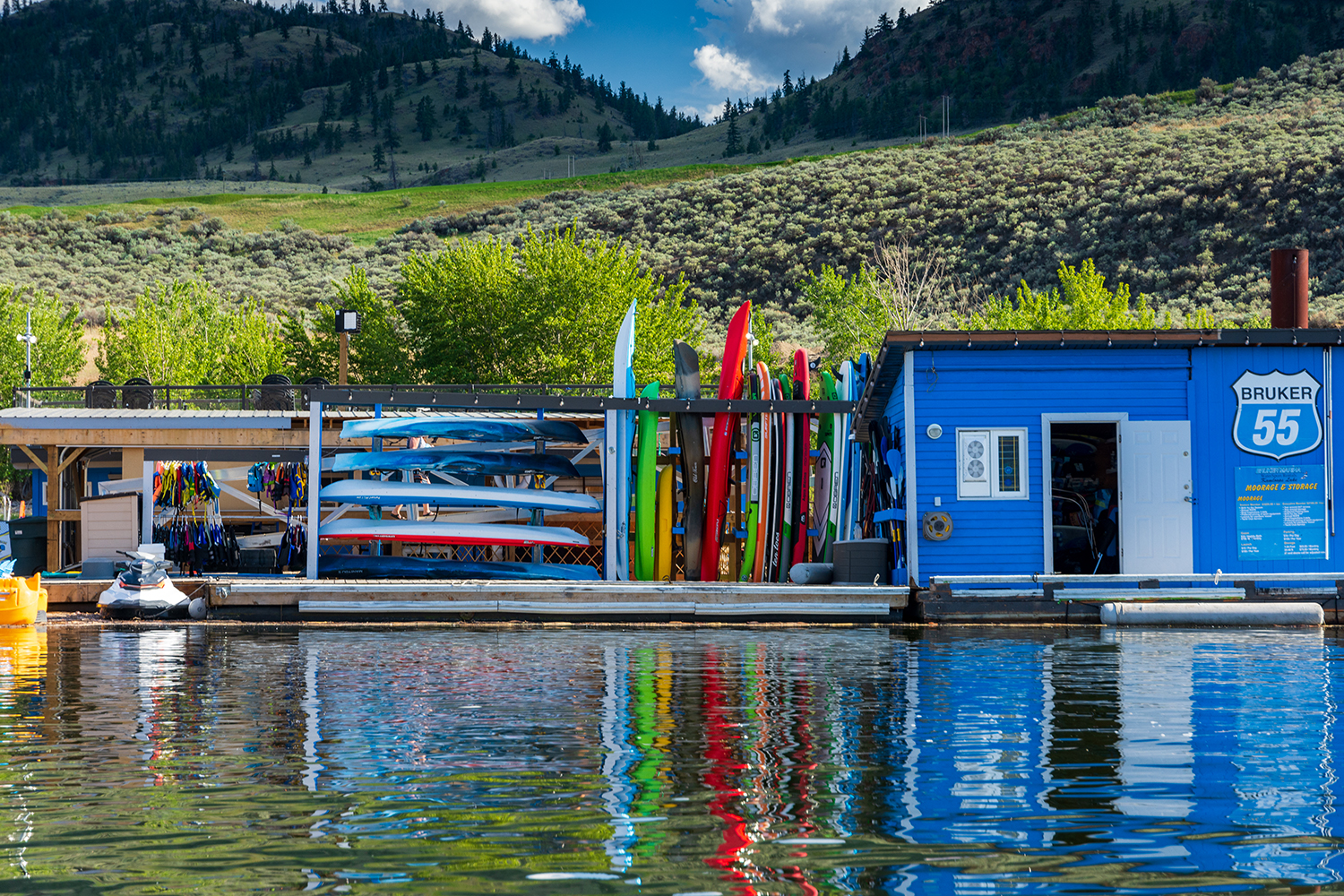 Kamloops Other boathouse with boats and jet skis on the water with a mountain