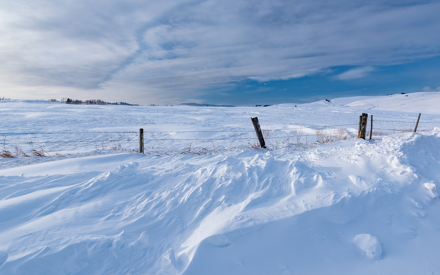 Kamloops Landscape snow covering wooden fence with bright sky and clouds