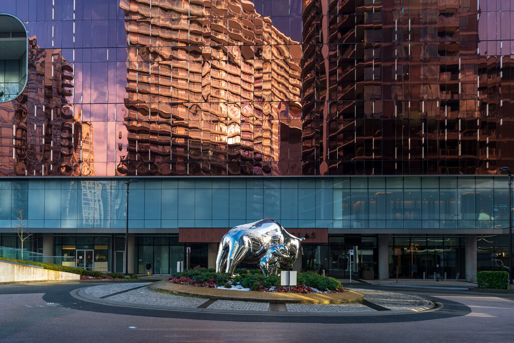 An idol of bull in silver color in front of a building
