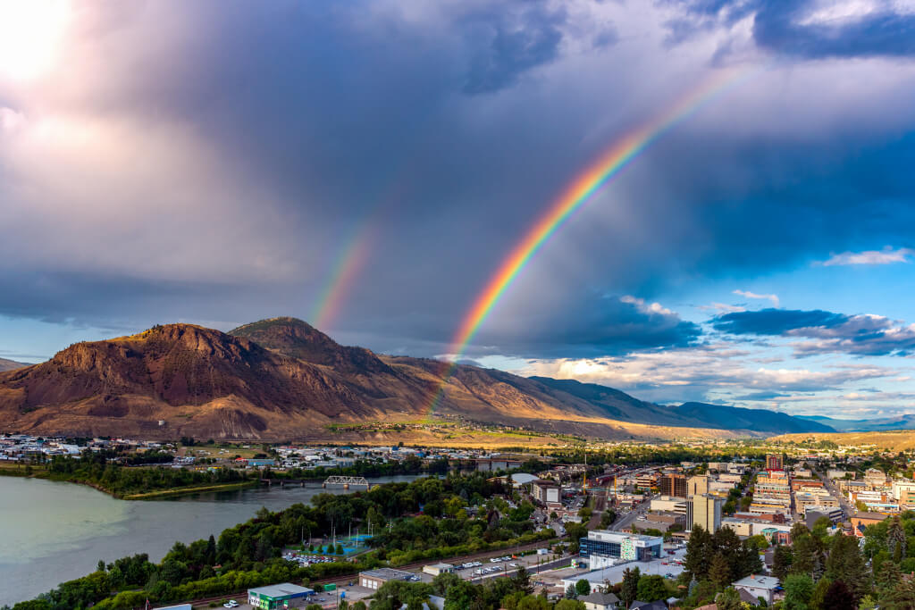 View of river and mountain with rainbow and clouds