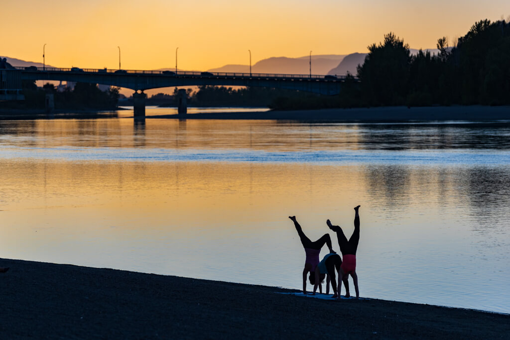 Three people doing handstands in front of the lake