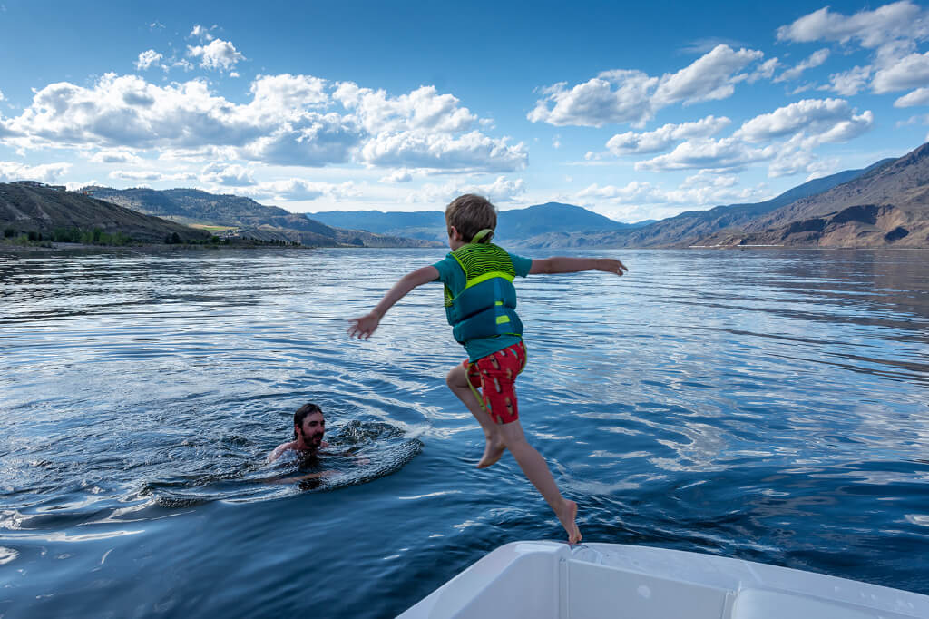 A child jumping out of a boat into the water