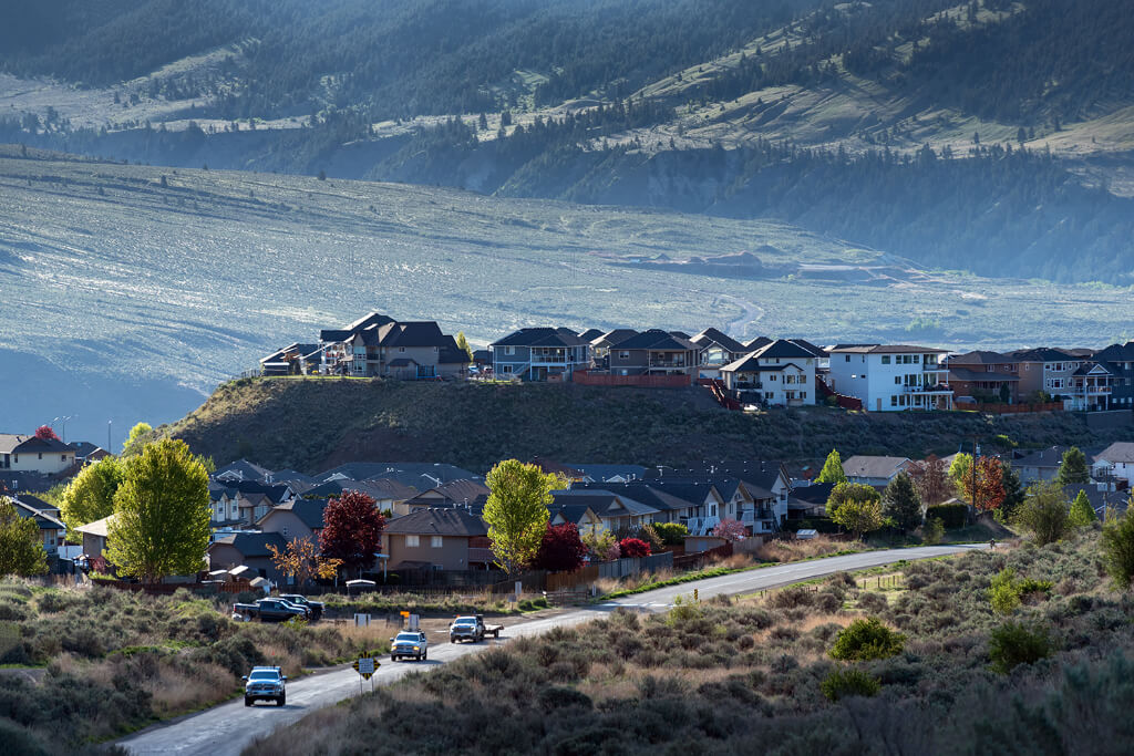 Houses along the hills with curving road and cars