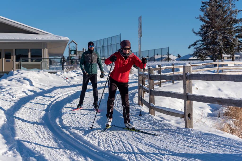 Couple in a ski slope with wooden fences doing skiing