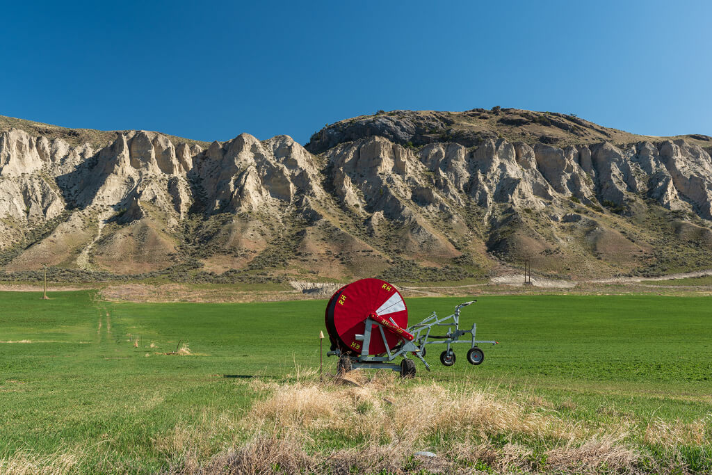 A red machine in a field with mountains and green grass